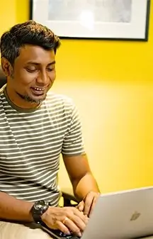 A IT professionals working with macbook behaind yellow wall